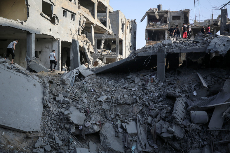Mieszkańcy Strefy Gazy sprawdzają budynki zniszczone podczas izraelskiego nalotu w obozie dla uchodźców Al-Maghazi w środkowej Strefie Gazy, 3 listopada 2023 r.