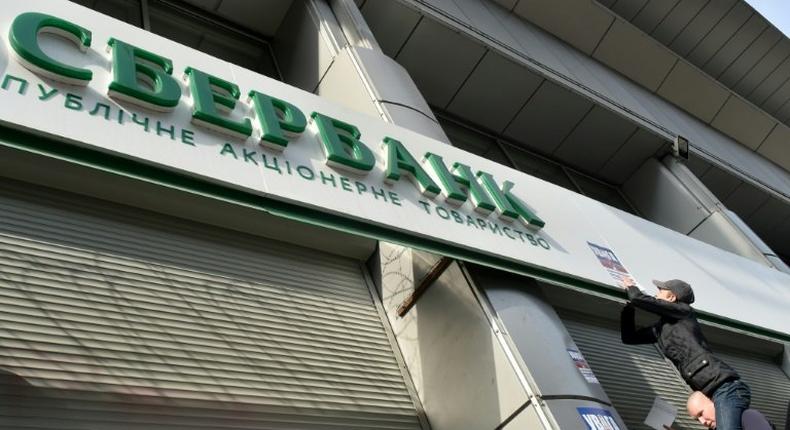 Activists of Ukraine's National Corps party stick placards on the shuttered entrance of a Russian Sberbank branch during a protest in Kiev on March 10, 2017