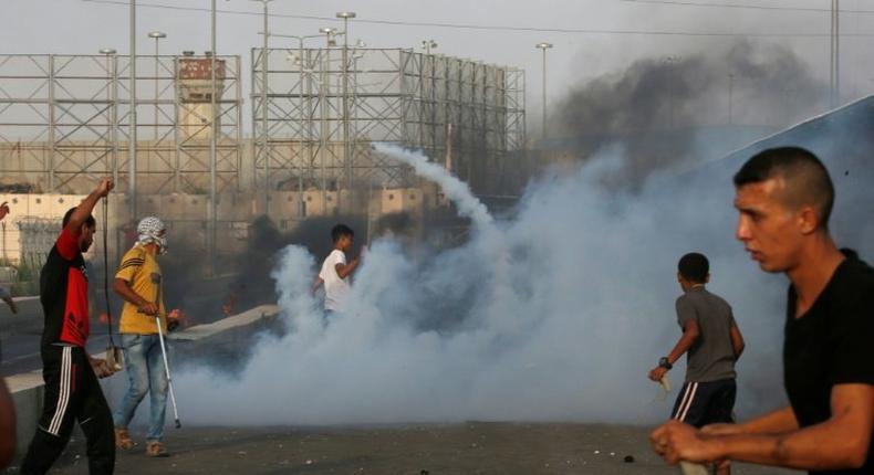 Palestinian protesters demonstrate amid tear gas fired by Israeli troops at the Erez border crossing with Israel in the northern Gaza Strip on October 3, 2018