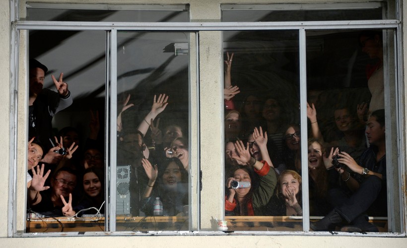 Widzowie obserwujący czerwony dywan przez okno