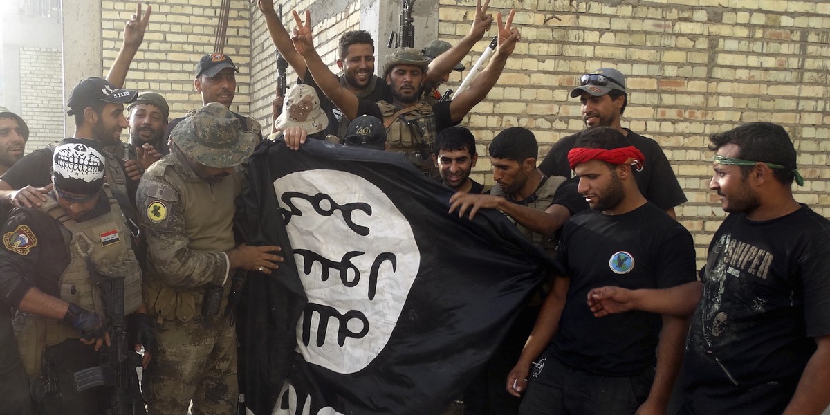 Iraqi security forces with an ISIS flag they pulled down at the University of Anbar, in Anbar province, July 26, 2015.