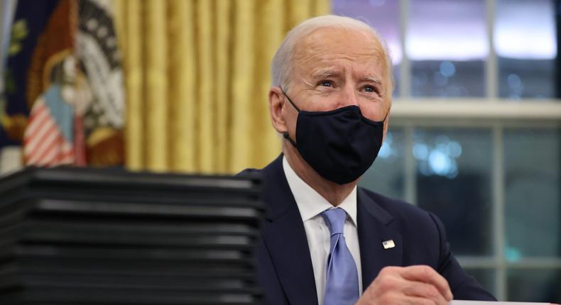 President Joe Biden prepares to sign a series of executive orders at the Resolute Desk in the Oval Office.