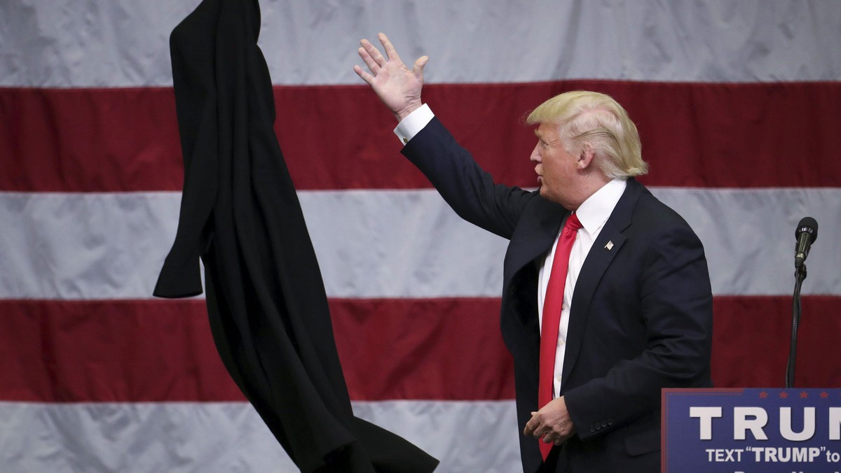 U.S. Republican presidential candidate Donald Trump tosses off his overcoat as he speaks at a campai