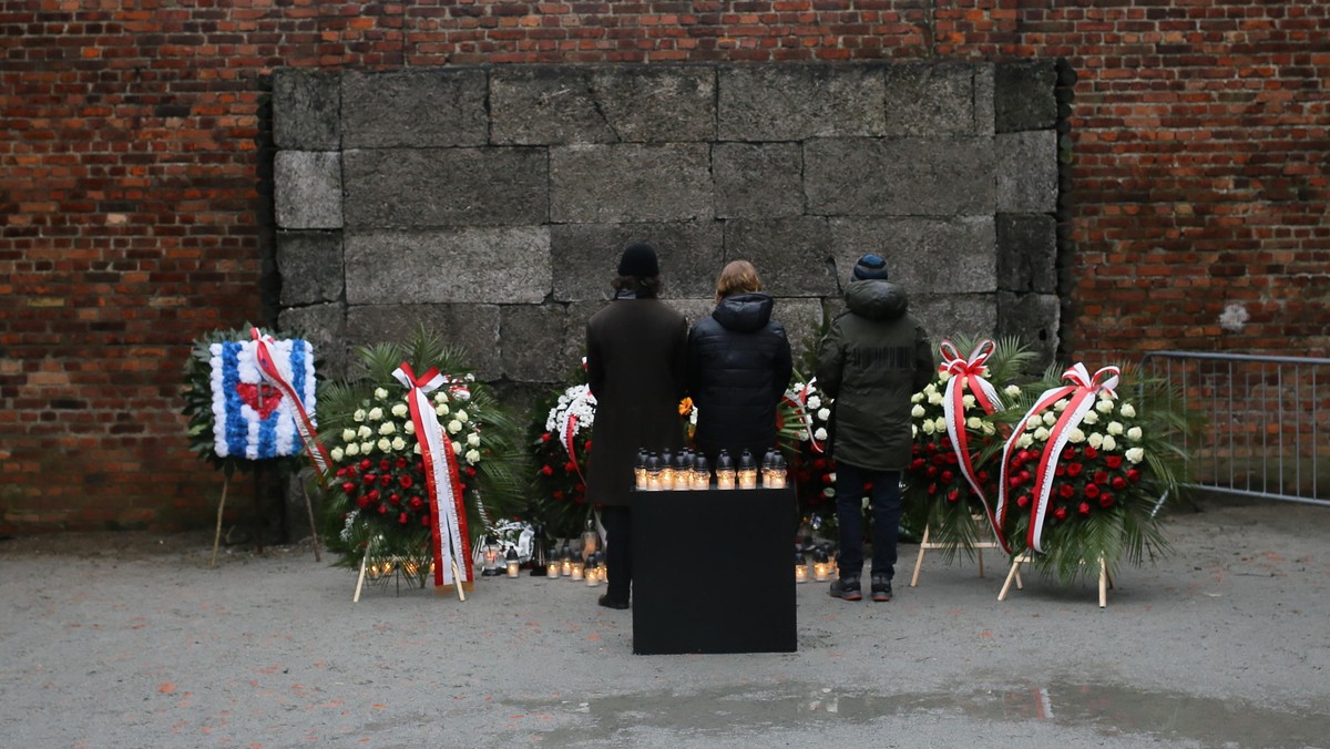 Złożenie kwiatów i zapalenie zniczy przed Ścianą Śmierci na terenie byłego niemieckiego nazistowskiego obozu koncentracyjnego i zagłady Auschwitz-Birkenau w Oświęcimiu