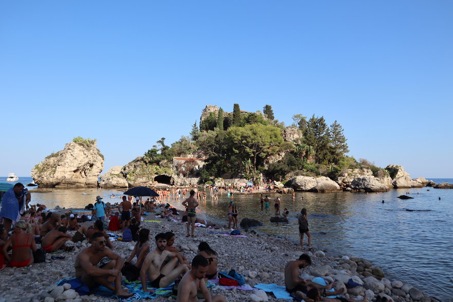 Gęsto zajęta plaża w Taorminie z widokiem na Isola Bella