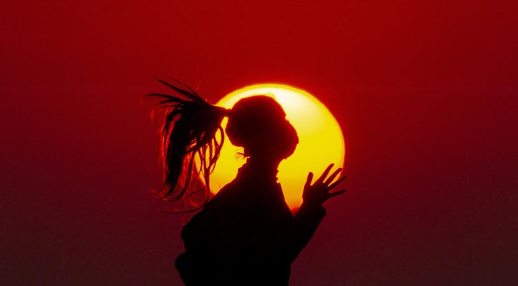 Védőmaszkot viselő lány kocog naplementekor a Földközi-tenger partján, Bejrútban 2020. április 14-én, a koronavírus világjárvány idején
