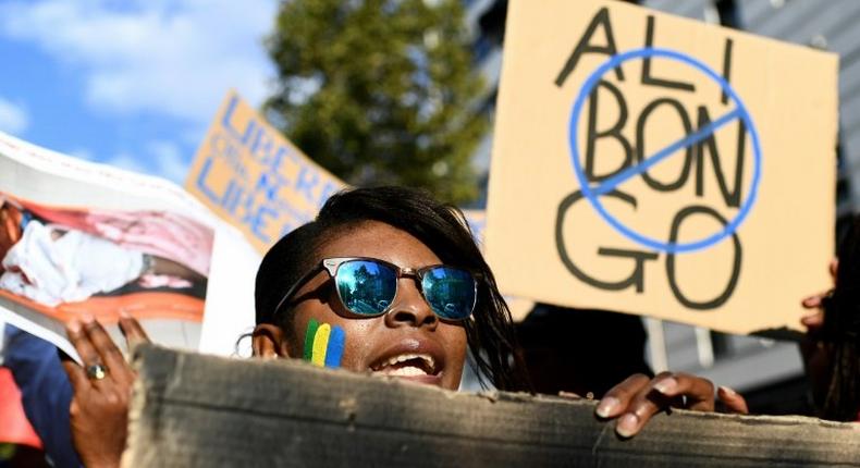 People hold a banner and photos during a demonstration of Gabonese associations in Marseille, southern France on September 24, 2016 to protest against the validation of reelection of Gabon's president Ali Bongo