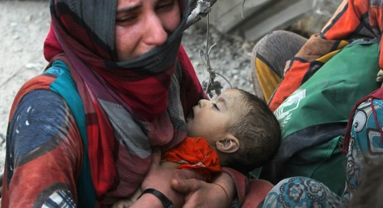 An Iraqi woman carries a child as she flees the Old City of Mosul on July 5, 2017