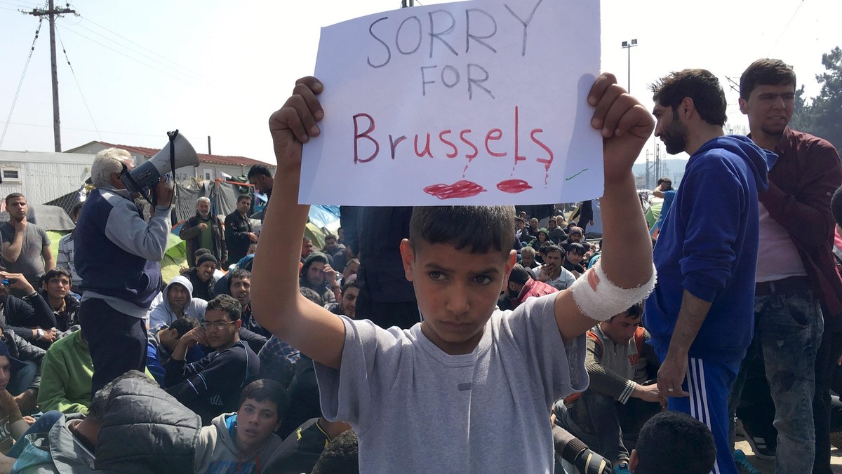 A refugee boy holds up placard reading Sorry for Brussels as refugees and migrants take part in a 