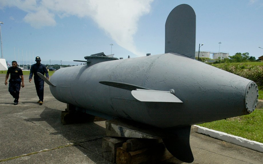 Two officials walk past a submersible craft used to smuggle cocaine under water to avoid detection, in Buenaventura June 13, 2008. Colombians who thought they had seen everything in the war on drugs were treated to something new this year: cocaine smuggling in a submarine. Picture taken on June 13, 2008.