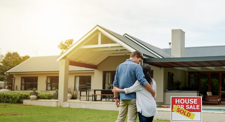 A couple standing in front of a home.