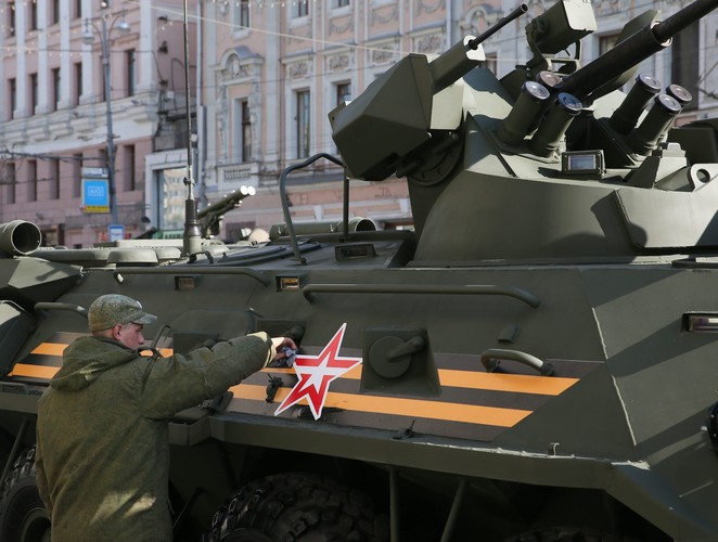 Rosyjski żołnierz czyści opancerzony pojazd wojskowy podczas próby generalnej parady wojskowej w Moskwie.