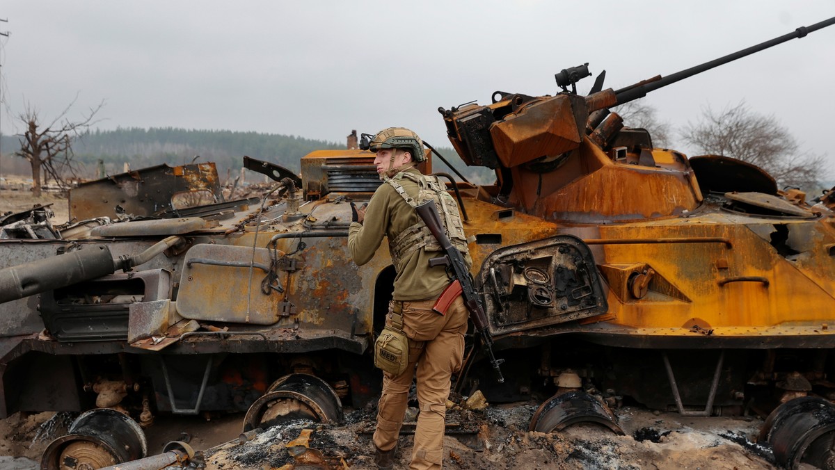 Ukraiński żołnierz przeprowadza inspekcję zniszczonego rosyjskiego BTR-82 we wsi w pobliżu linii frontu w obwodzie kijowskim