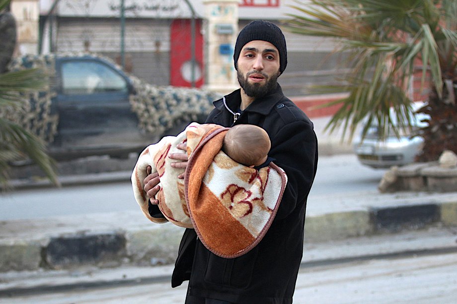 A man carries a child as he flees deeper into the remaining rebel-held areas of Aleppo, Syria December 12, 2016.