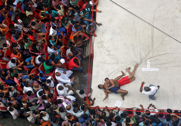 Wrestlers fight during an amateur wrestling match inside a makeshift ring installed on a road organi