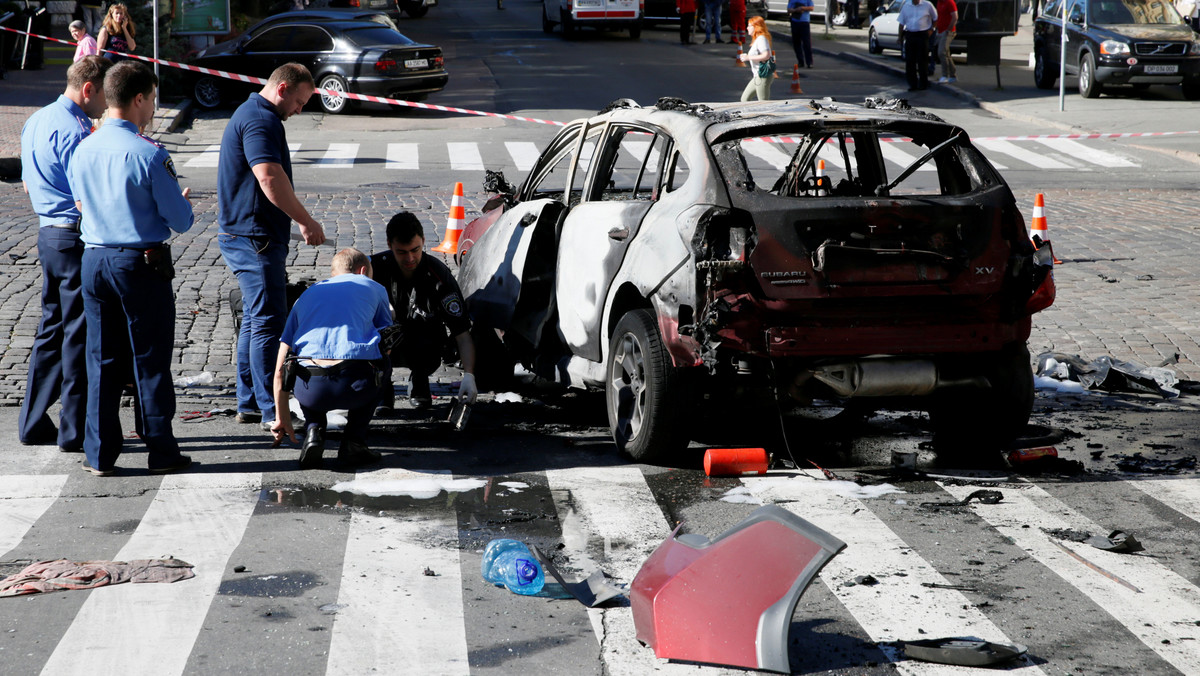Investigators inspect a damaged car at the site where journalist Pavel Sheremet was killed by a car bomb in central Kiev