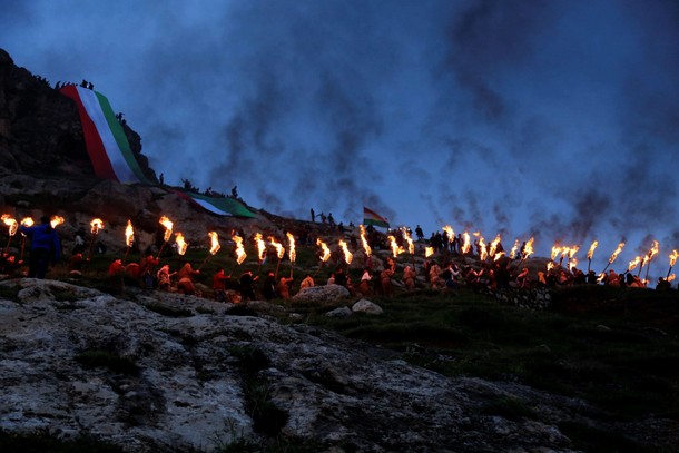 Iraqi Kurdish people carry fire torches up a mountain, as they celebrate Newroz Day, a festival mark