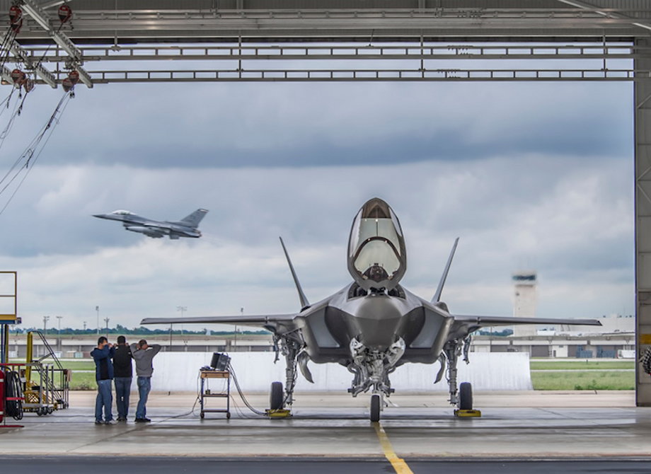 Big and Little Brother: An F-35A sits in a run station on the Fort Worth, Texas, flight line, while an F-16 Fighting Falcon, also produced at the Fort Worth plant, takes off in the background. Learn more about F-35 production.