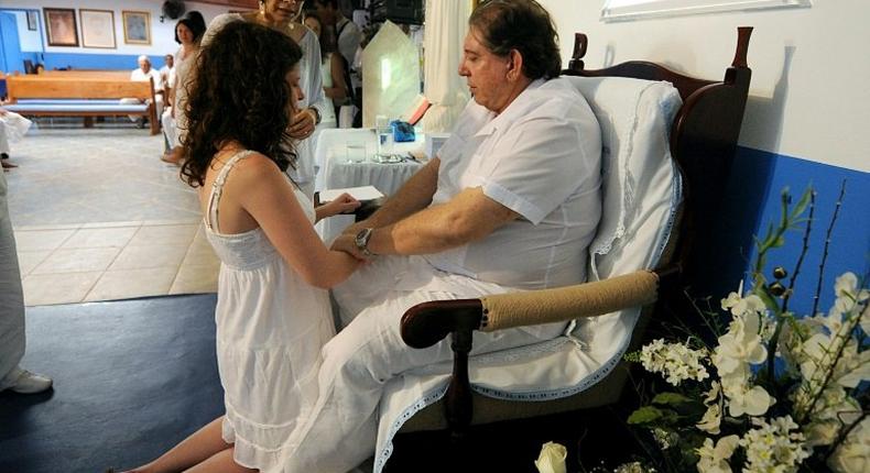 Several women have accused Brazilian 'spiritual healer' Joao Teixeira de Faria, or 'Joao of God,' of sexually abusing them under pretext of helping cure them of various problems; he is seen here with a patient in a 2012 file photo taken in the city of Abadiania, near Brasilia