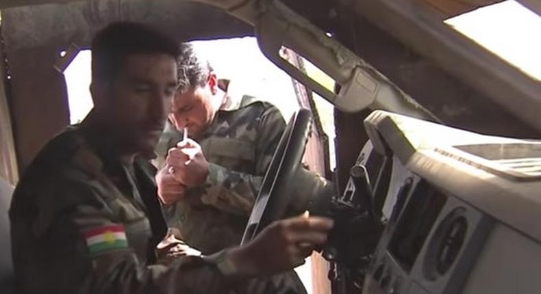 YPG fighters sit and look inside a captured VBIED.