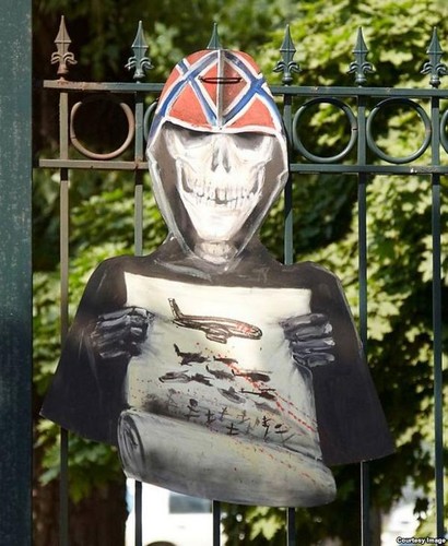 Kostucha z kartką z wizerunkiem malezyjskiego samolotu, strąconego nad wschodnią Ukrainą - praca Siergieja Zacharowa / źródło: @apravda