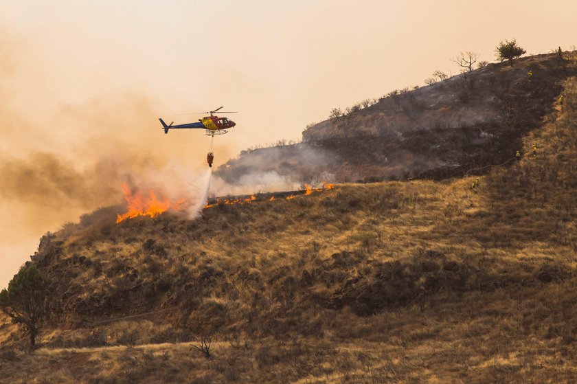 Flames and smoke from a forest fire are seen in the village of Valleseco