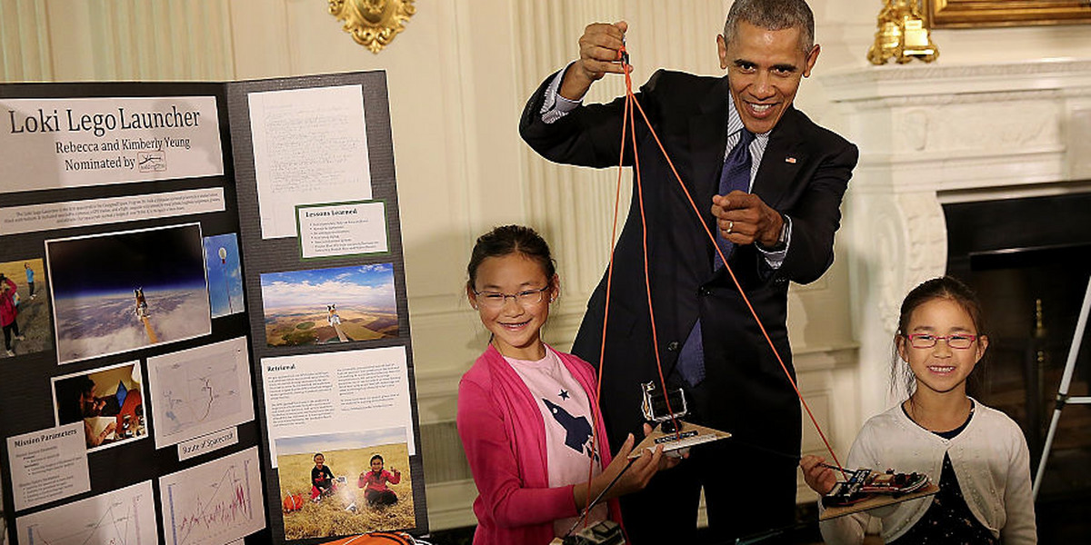 Barack Obama listens to sisters Kimberly Yeung (R) and Rebecca Yeung (L) explain their science project while touring exhibits at the White House Science Fair April 13, 2016 in Washington, DC.