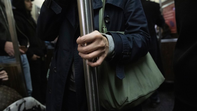 A commuter holds on to a vertical pole as she rides the subway, Wednesday, March 4, 2020, in New York.