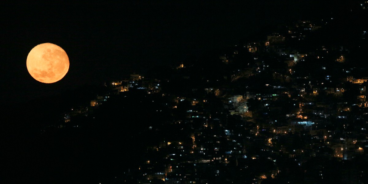 The moon sets behind the Vidigal favela in Rio de Janeiro.