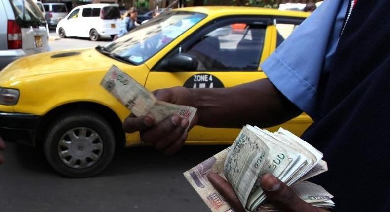 A fuel attendant handles Kenyan shilling notes at a petrol station in the capital Nairobi March 15, 2011.    REUTERS/Noor Khamis