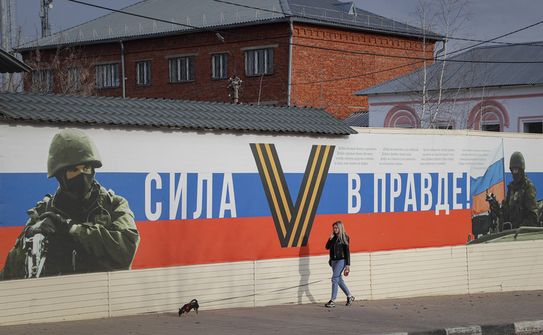 W wielu rosyjskich miastach łatwo dostrzec propagandowe murale i plakaty. Na zdjęciu kobieta przechodzi przed transparentem z hasłem: "Siła w prawdzie” w mieście Jefremow, obwód tulski, Rosja, 6 kwietnia 2023 r.