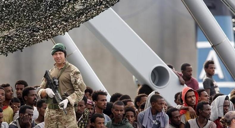 Migrants are seen aboard the British vessel HMS Enterprise before disembarking in the Sicilian harbour of Catania, Italy, October 6, 2015. REUTERS/Antonio Parrinello