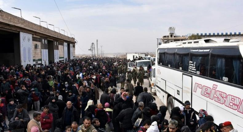 Syrian families, fleeing from various eastern districts of Aleppo, queue to get onto buses on November 29, 2016