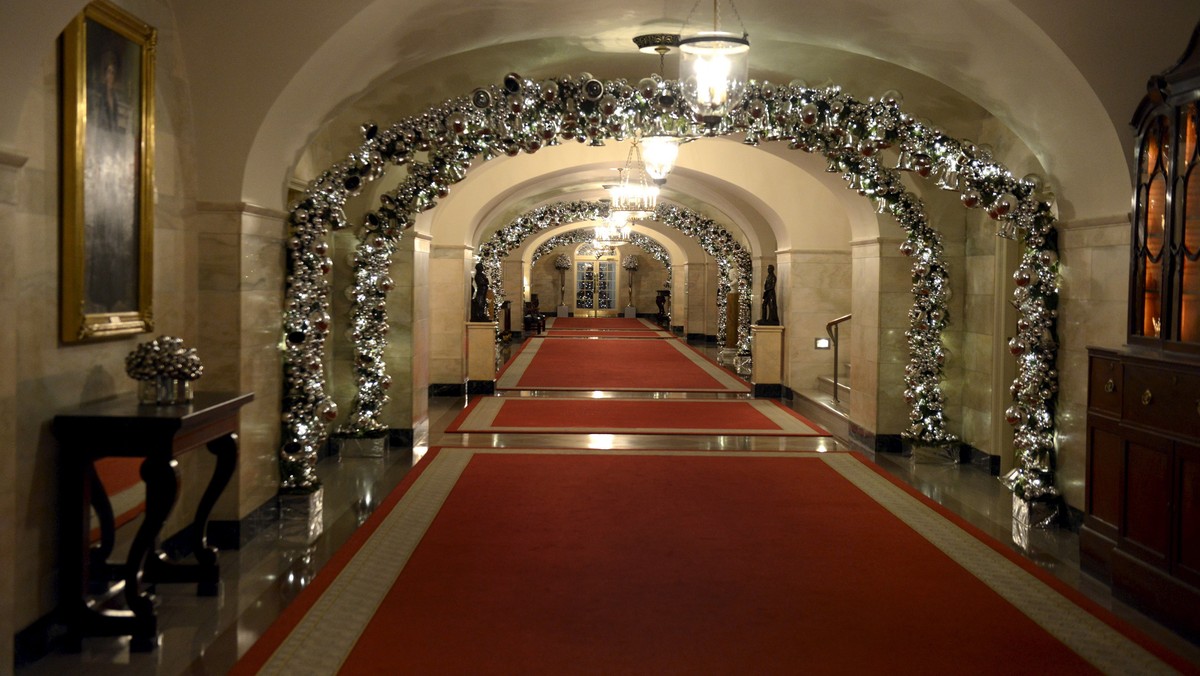 A hallway of the White House features silver arches aglow, a preview of holiday decorations being assembled for the season, in Washington