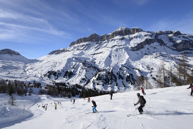 Dolomity: descending toward Pordoi pass, Arabba; skiers on bright snow over steep ski run in Dolomites in important ski area