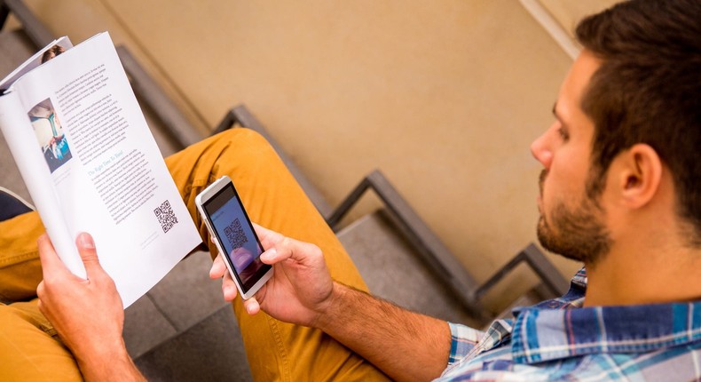 A man scans QR Code in a magazine.
