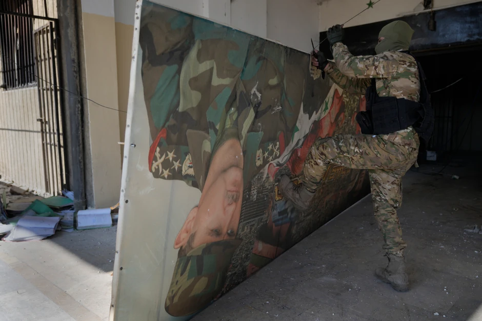 Sirijski pobunjenik sklanja plakat sa likom svrgnutog predsednika Bašara al Asada u Damasku 14. decembra