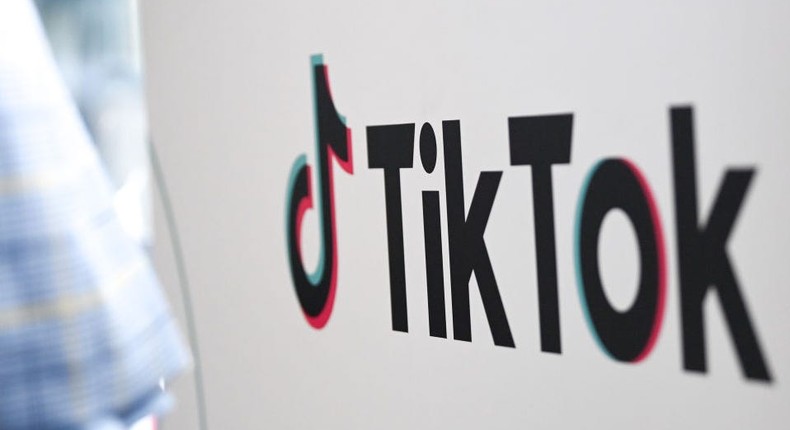 A person walks past a sign for TikTok.