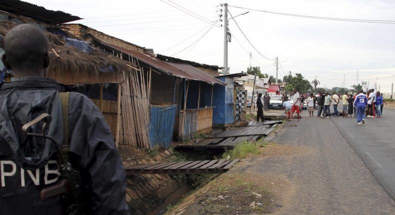 A policeman watches as residents gather near the bodies of unidentified men killed during gunfire in the Nyakabiga neighborhood of Burundi's capital Bujumbura, December 12.