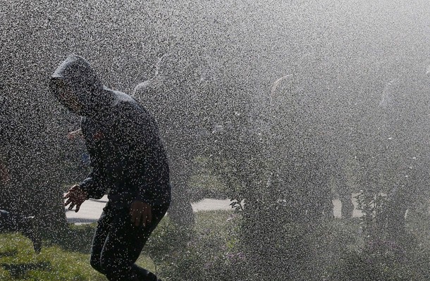 A demonstrator is sprayed by a jet of water from a riot police vehicle during a rally called by stud