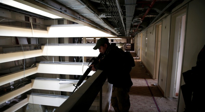 An Iraqi soldier holds his weapon while looking over a balcony in the Ninewah Oberoi Hotel in Mosul.