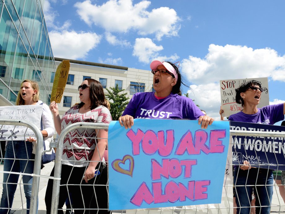 People demonstrate outside the hall where Education Secretary Betsy DeVos delivered a major policy address on Title IX enforcement.