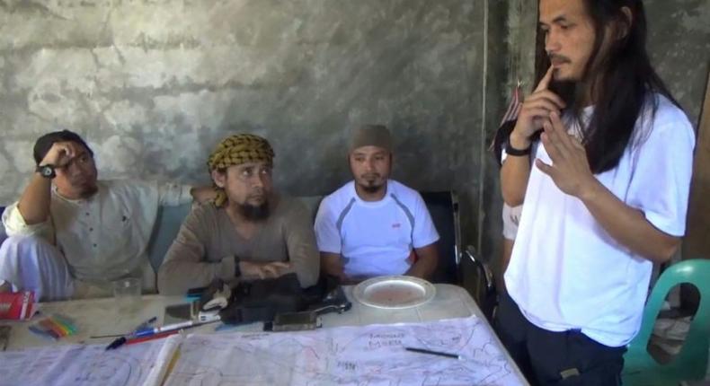 Screengrab taken from video released by the Philippine Army on June 18, 2017 shows Isnilon Hapilon (2nd L), leader of hardline group Abu Sayyaf, and Abdullah Maute (R) discussing an improvised map of Marawi at an undisclosed location on Mindanao