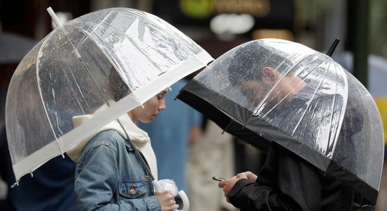 A couple shelter under an umbrellas as rain falls in Sydney, Friday, Feb. 7, 2020, while the Bureau of Meteorology issued severe weather warning along the New South Wales state coast. The rain comes as a slight relief for some areas dealing with wildfires that devastated large swathes of land across the state over the last several months. (AP Photo/Rick Rycroft)