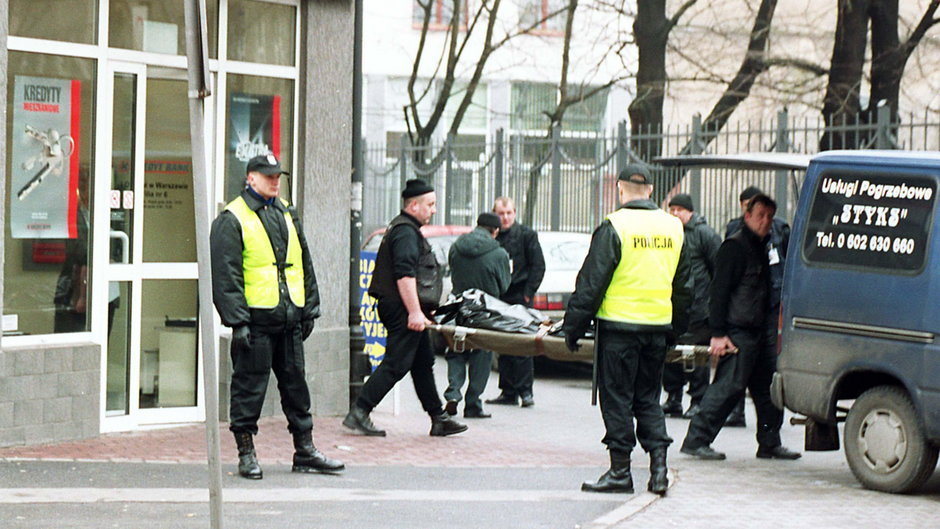 Pracownicy firmy pogrzebowej wynoszą z oddziału Kredyt Banku w Warszawie ciało jednej z osób zastrzelonych podczas napadu