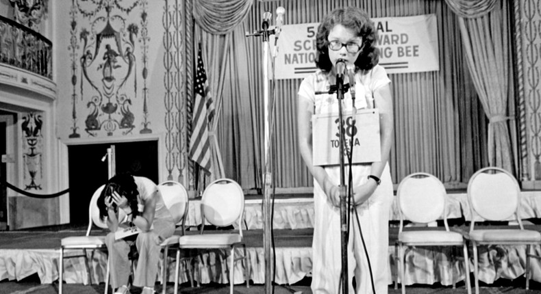 Peg McCarthy of Topeka, Kansas, spells the world deification to win the 51st National Spelling Bee in Washington, D.C., June 8, 1978. The runner-up Lyn Sue Kahng, seated left, puts her head in her hands