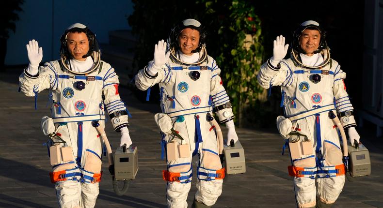 Left to right: Tang Hongbo, Nie Haisheng, and Liu Boming wave as they prepare to board for liftoff at the Jiuquan Satellite Launch Center in Jiuquan in northwestern China, June 17, 2021.
