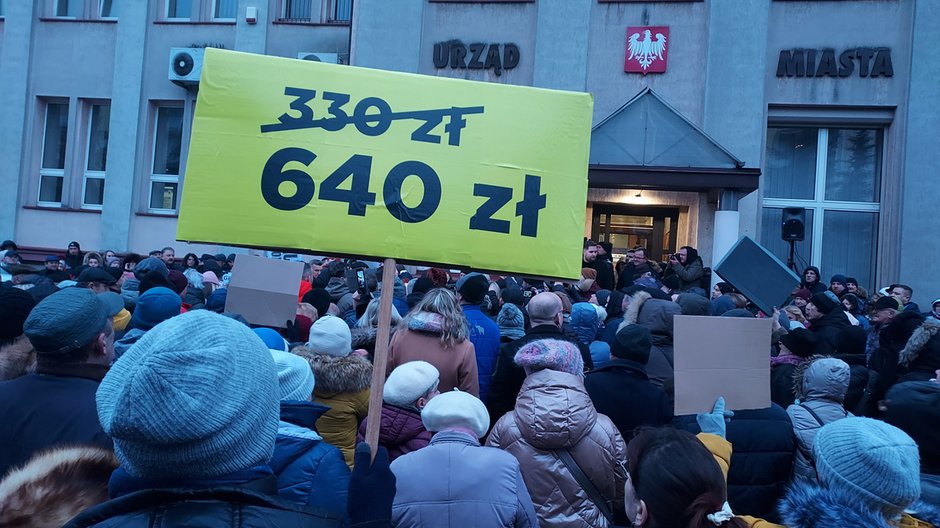 Demonstracja przeciwko ogłoszonym w 2023 r. cenom ciepła w Piotrkowie. Była ona wymierzona w prezydenta miasta, który na początku kariery był związany z PiS. Teraz jego ostrym przeciwnikiem jest obecny radny tej partii. Jednak ubiega się on o urząd prezydenta bez barw partyjnych