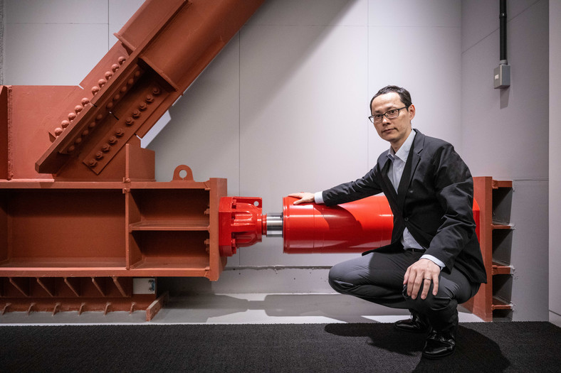 Kai Toyama, urzędnik ds. inżynierii strukturalnej w gigancie nieruchomości Mori Building, pokazuje amortyzator olejowy w Toranomon Hills Business Tower w Tokio.