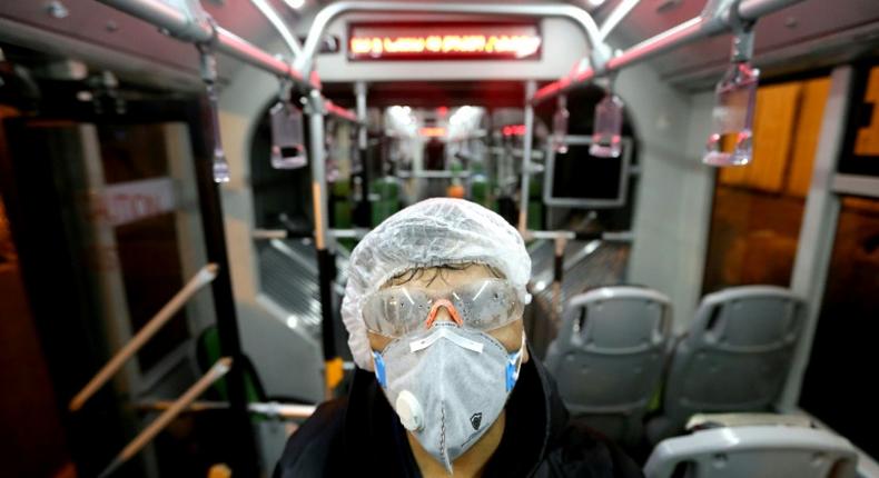 A city council worker in protective clothing disinfects a bus in Tehran as part of government efforts to control a novel coronavirus outbreak that has now killed 19 people